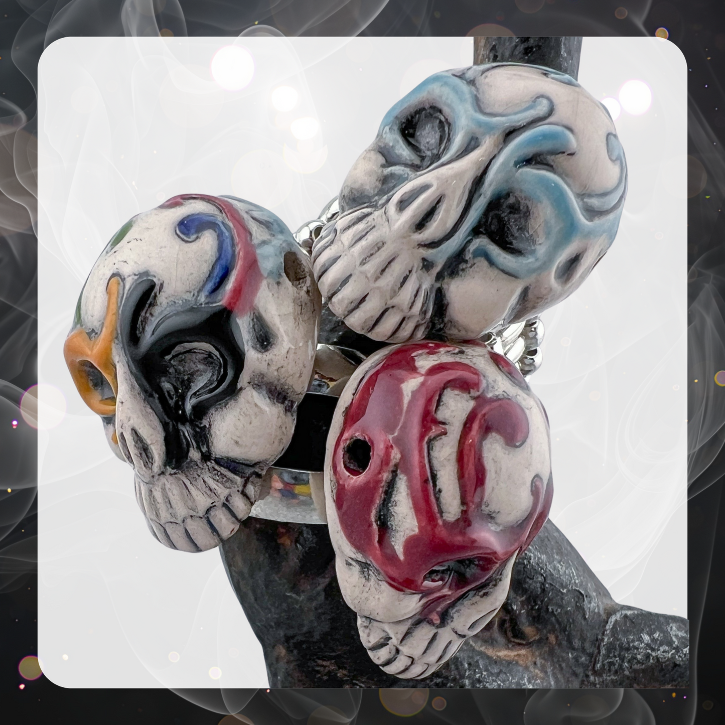 Picture shows three glazed ceramic decorated sugar skulls made into rings. There is a blue one, a red one, and a multi color one that has black, red, yellow, and blue.