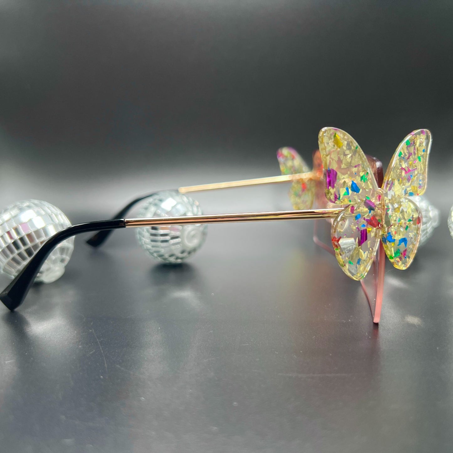 Butterfly Shield Sunglasses – Oversized and enchanting eyewear for standing out at festivals and raves. Displayed on a table. Side view.