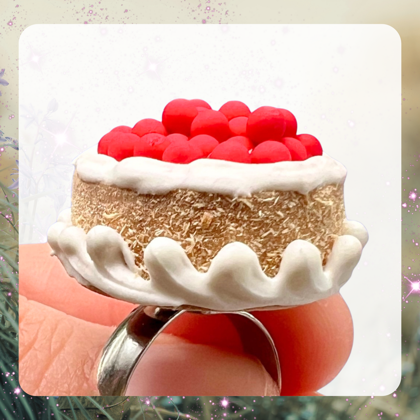 A picture of a miniature dollhouse cherry cheesecake that had been made into a cocktail ring. 