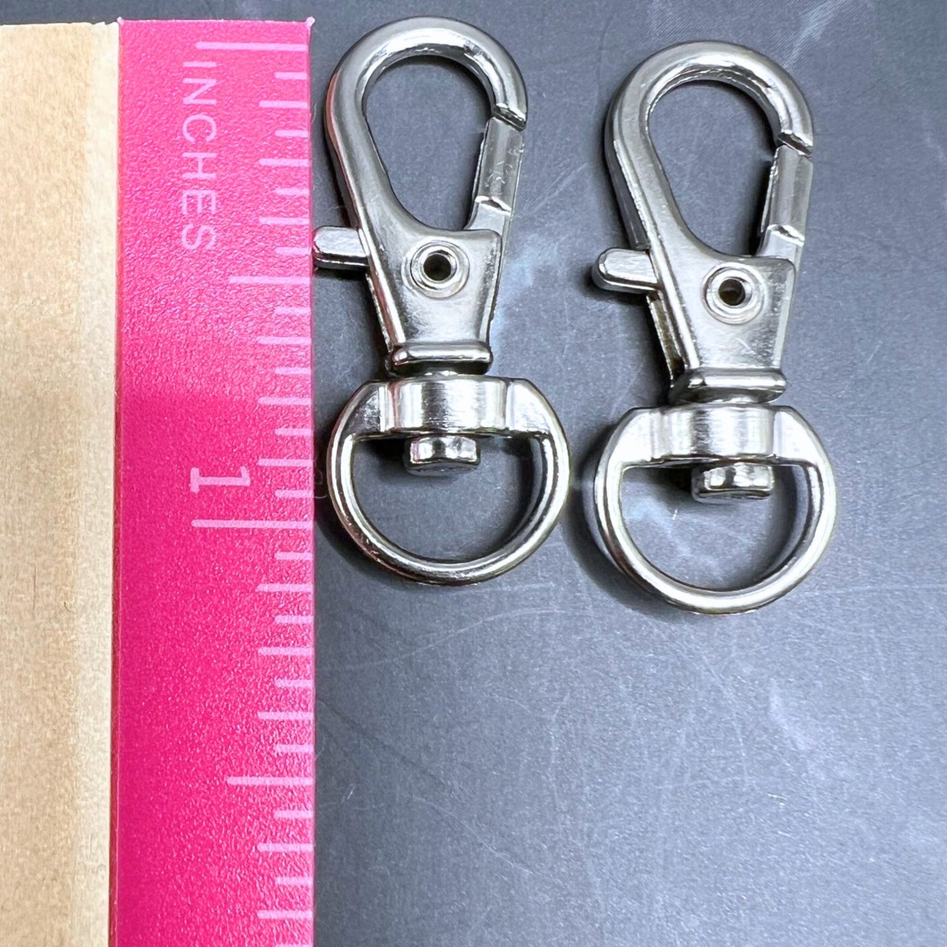 Swivel clips displayed on a table with a ruler showing the length as 1".