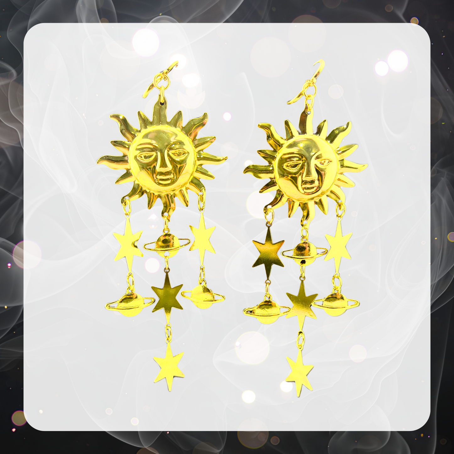 A pair of golden sun dangle earrings with stars and planets shaped like Saturn. 