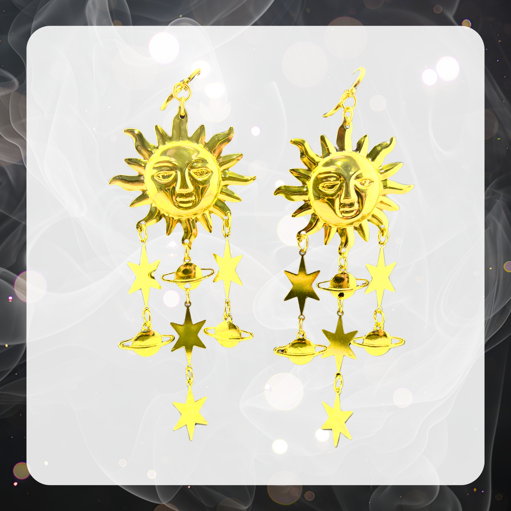 A pair of golden sun dangle earrings with stars and planets shaped like Saturn. 