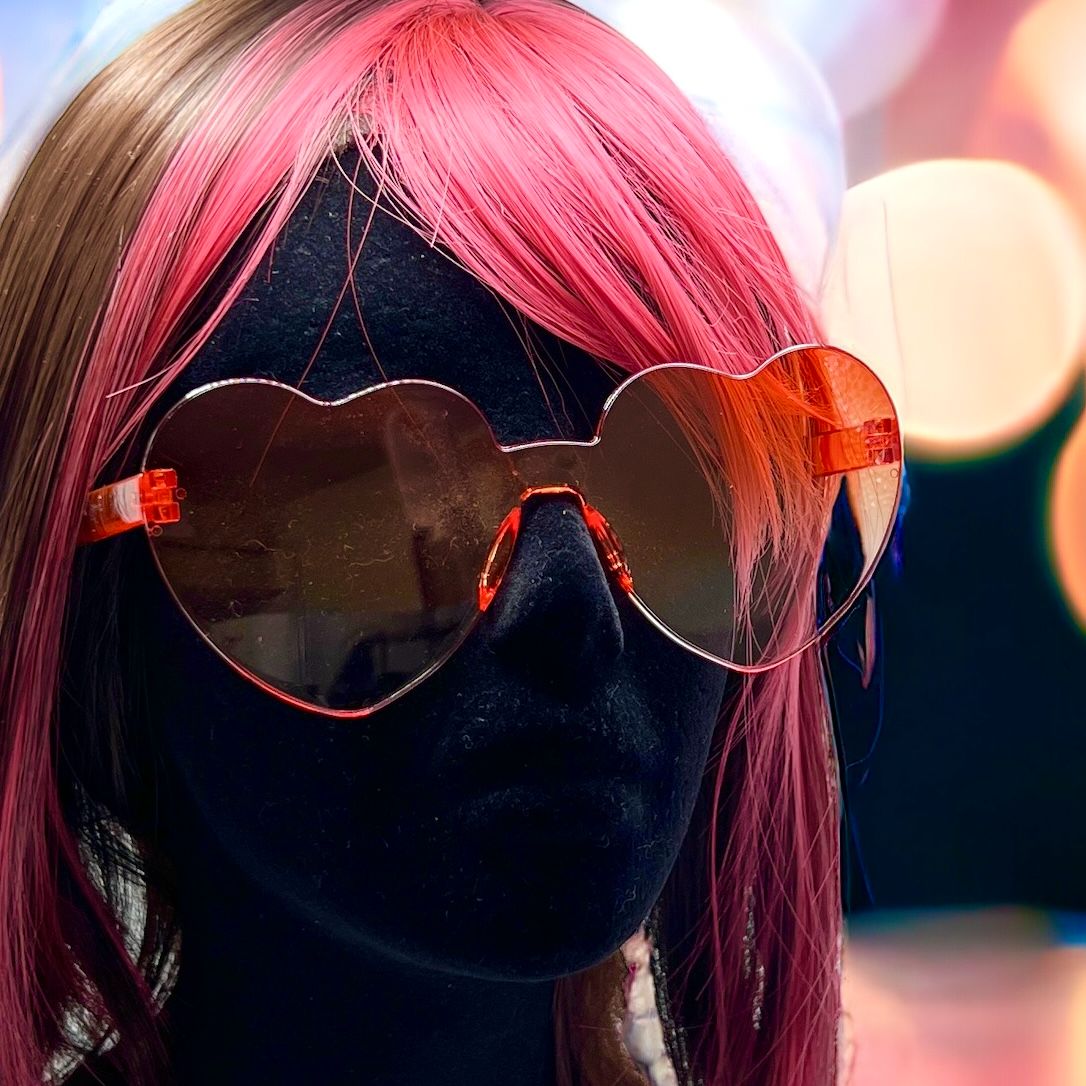 Colorful oversized heart-shaped sunglasses, perfect for festivals and dancing. Lightweight and trendy eyewear for a vibrant and stylish look. Displayed on a mannequin.