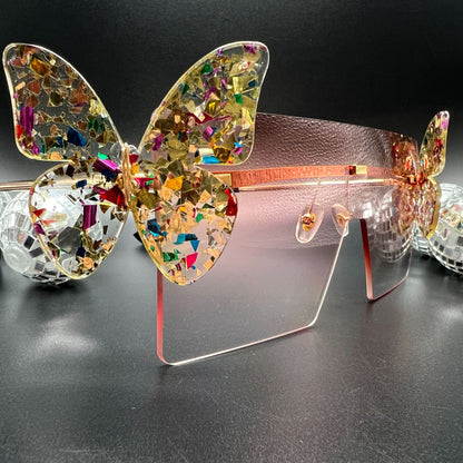 Butterfly Shield Sunglasses – Oversized and enchanting eyewear for standing out at festivals and raves. Displayed on a table. Front view.