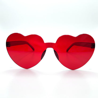 Colorful oversized heart-shaped sunglasses, perfect for festivals and dancing. Lightweight and trendy eyewear for a vibrant and stylish look. Displayed on a table. Front view. Red Heart.