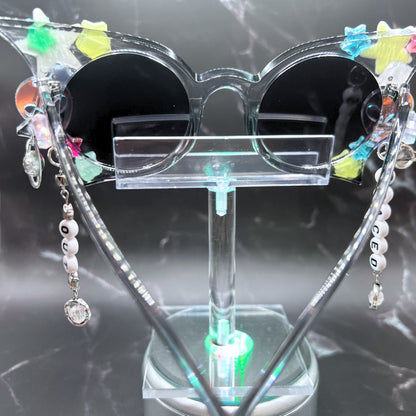 Hypnotic Space Alien Sunglasses with glow-in-the-dark stars and alien charms for a cosmic rave experience! Displayed on a clear stand. Back view.