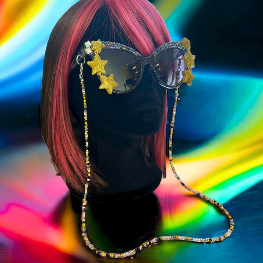 Yellow glitter star sunglasses with rhinestones and detachable beaded chain. Displayed on a mannequin.