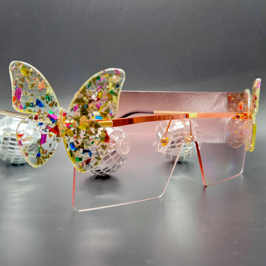 Butterfly Shield Sunglasses – Oversized and enchanting eyewear for standing out at festivals and raves. Displayed on a table. Front view.