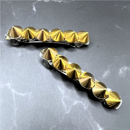 Edgy goth hair barrettes with silver, gunmetal, or gold spikes. Displayed on a table. Short gold clips.