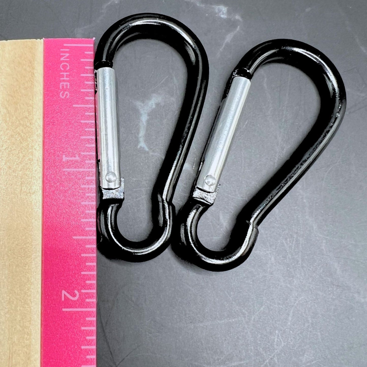 Black carabiner clips displayed next to a ruler showing the length as 1.5".