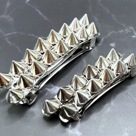 Edgy goth hair barrettes with silver, gunmetal, or gold spikes. Displayed on a table. Compares the gunmetal and silver colors and the long and short lengths.