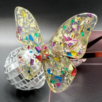 Butterfly Shield Sunglasses – Oversized and enchanting eyewear for standing out at festivals and raves. Displayed on a table. Front view, close up of butterfly.