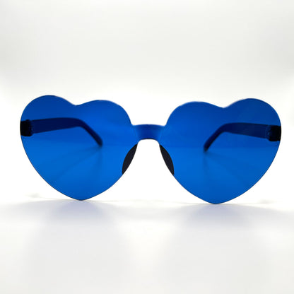 Colorful oversized heart-shaped sunglasses, perfect for festivals and dancing. Lightweight and trendy eyewear for a vibrant and stylish look. Displayed on a table. Front view. Royal Blue Heart.