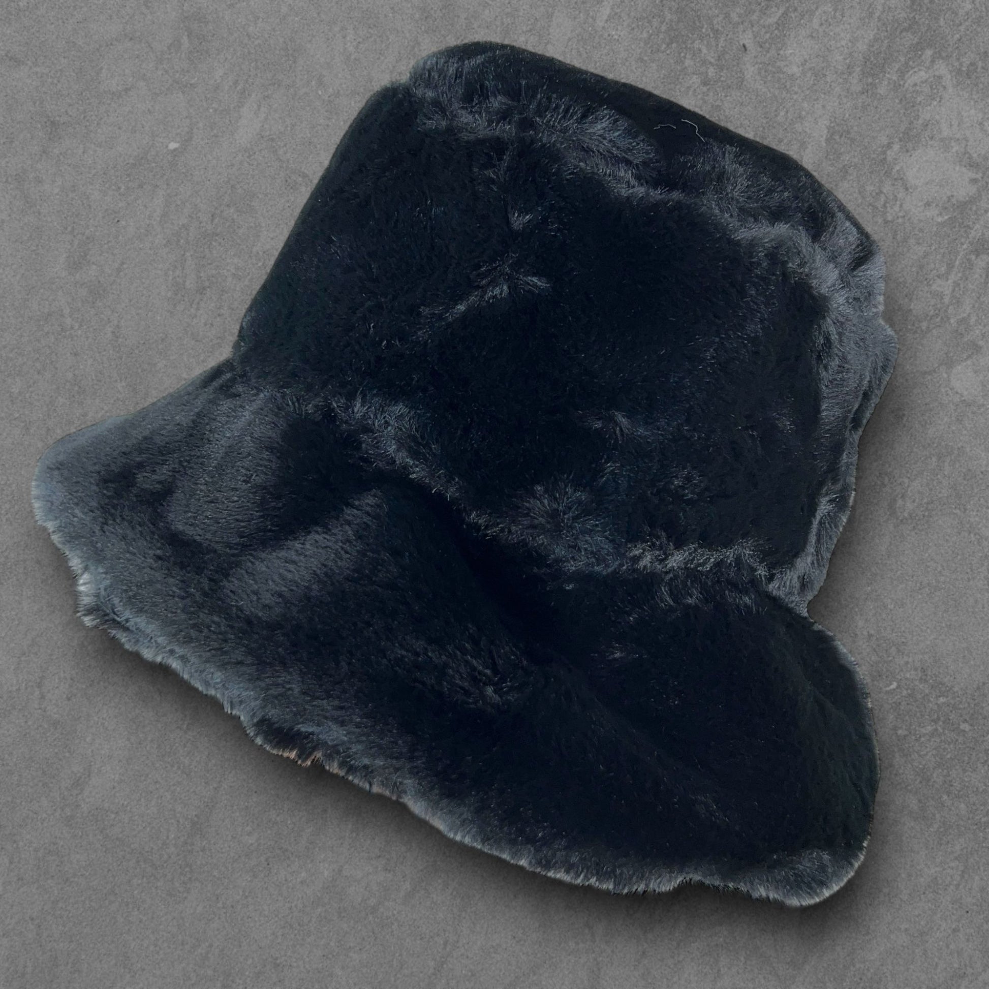 Gloomy Black Furry Festival Bucket Hat – sophisticated and stylish accessory for standing out at festivals and events. Displayed on a table. Front view.