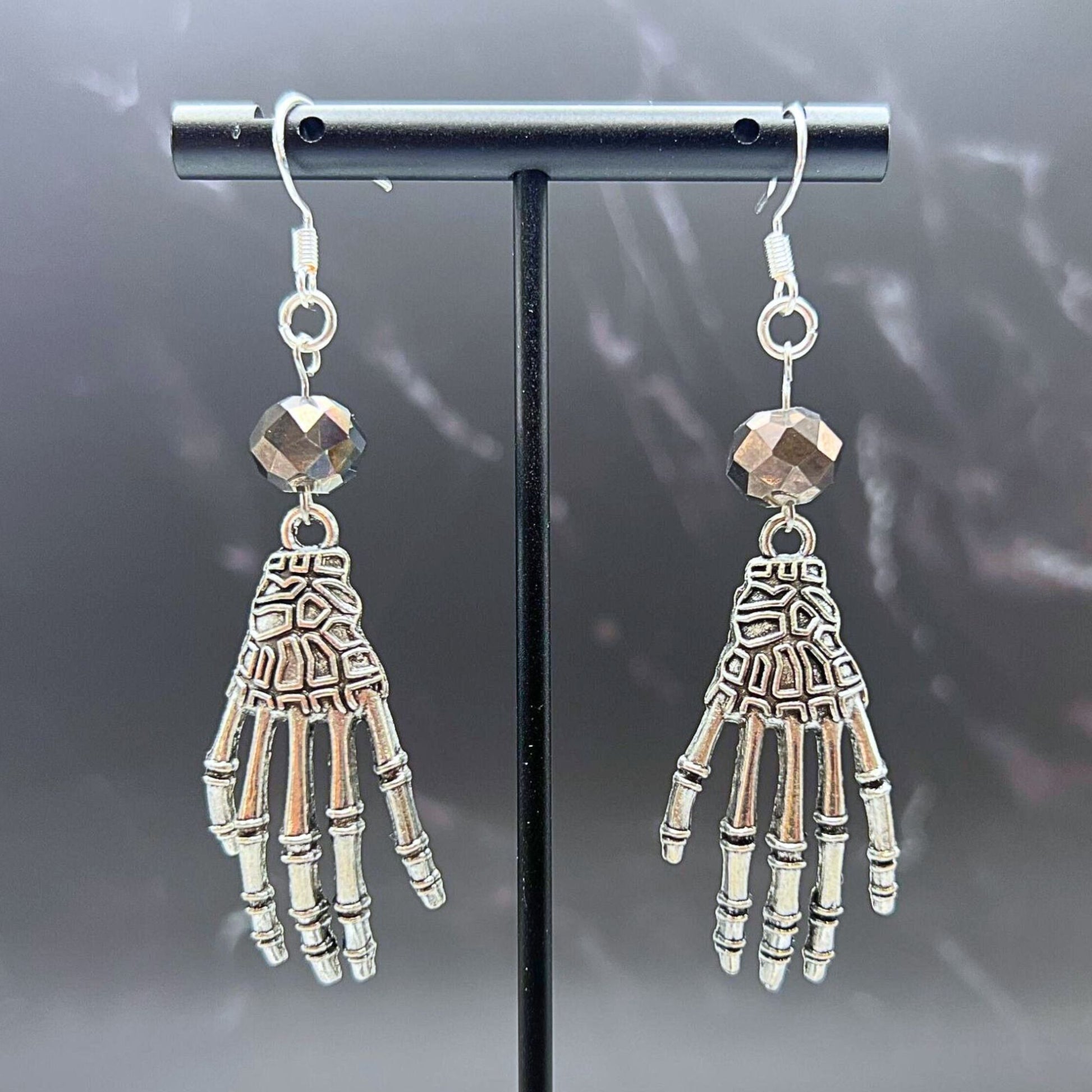 Skeleton Hand Beaded Earrings. Displayed on a clear stand.