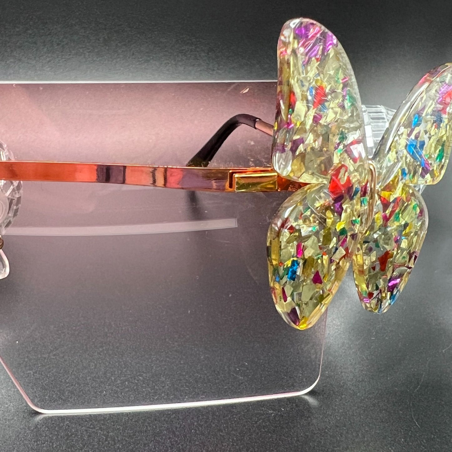 Butterfly Shield Sunglasses – Oversized and enchanting eyewear for standing out at festivals and raves. Displayed on a table. Front view, close up of butterfly.