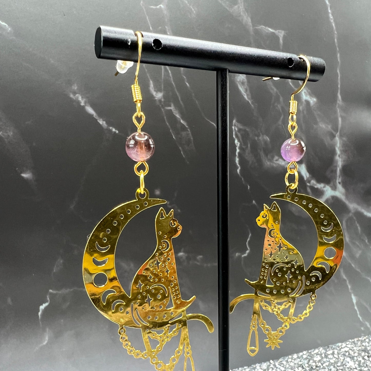 Close-up of Bohemian Beaded Cat Earrings featuring gold cat charms and purple crystal beads.