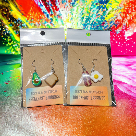 Close-up of Brunch Mini Food Earrings featuring cute Bacon, Eggs, and Avocado Toast charms. Quirky and delightful accessories for foodie fashion. Displays both pairs of available options in their packaging.